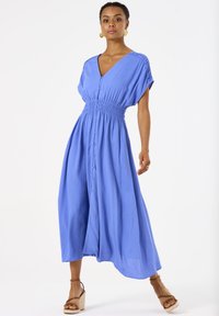 Blaues, knöpffreies Kleid mit V-Ausschnitt, smockiertem Taillenbereich und kurzen Ärmeln; aus leichtem Material mit einem schwingenden, bodenlangen Rock.