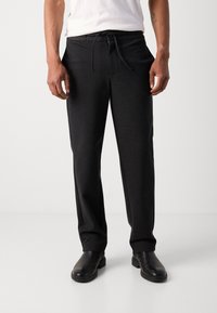 Pantalons de jogging noirs, ajustés avec une taille élastique et un cordon de serrage. Fabriqués en tissu doux, avec une texture lisse et des poches latérales.