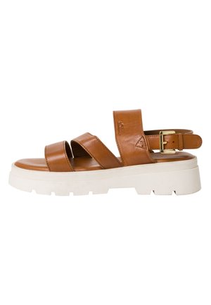 Sandale en cuir tan avec deux larges bretelles et une boucle, présentant une épaisse semelle blanche à surface texturée et striée.