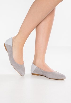 Šedé semišové baleríny s texturovaným světle šedým zadním panelem, mandlově tvarovanou špičkou a nízkou hnědou podrážkou. Hladký svršek a měkký povrch.