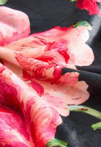 Blommig tyg med stora rosa och röda blommor på en svart bakgrund. Strukturerad yta med släta, mjuka draperingar.