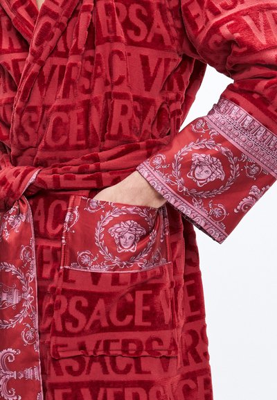 Červený župan z plyšové látky s vystouplými logy Versace a vzorovaným saténovým lemem s motivy Medúzy a propracovanými detaily.