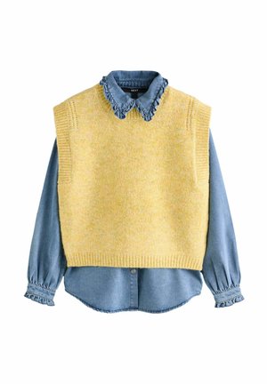 Keltainen neulottu hihaton neule, joka on kerrostettu sinisen farkkupaidan kanssa, jossa on röyhelökaulus ja pitkät puffihihat. Pehmeä rakenne ja rento design.
