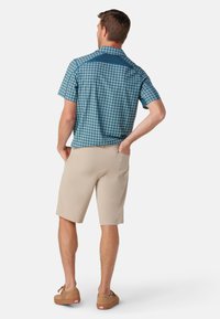 Blå og grøn ternet kortærmet skjorte parret med beige shorts, der har en glat tekstur og en afslappet pasform. Brune sko er på.