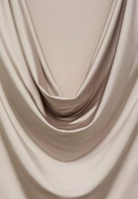 Tela beige drapeada con una textura suave y lisa, con pliegues delicados y un escote profundo. El material parece ligero y fluido.