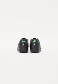 Black athletic shoes with a rubber sole, featuring green accents and a textured surface. Includes Italian flag detail on the heel.