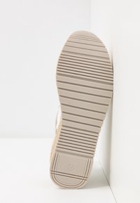 Beige gummisulor med texturerade ränder, med en vävd ovandel som kompletterar designen, med storlek 37 markerad på botten.