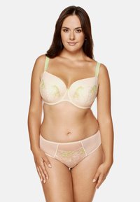Beżowy biustonosz i pasujące majtki z delikatnym zielonym haftem floralnym. Biustonosz ma usztywniane miseczki i regulowane jasnoszare ramiączka.