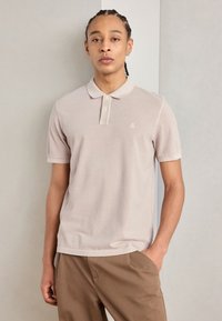 Lys grå polo skjorte i en myk bomullsblanding, med klassisk krage, to-knaps placket og et brodert logo på brystet.