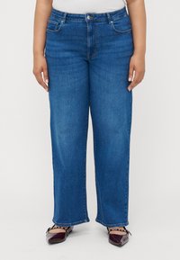 Platums kāju zili džinsi, izgatavoti no denima, ar klasisku piecu kabatu dizainu, jostu cilpām un pogu aizdari jostasvietā.