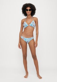 Bikini komplet svijetloplave boje, s raznobojnim cvjetnim i morskim zvjezdicama uzorcima. Halter top i donji dijelovi s niskim strukom s glatkom teksturom.