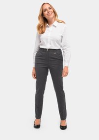Maßgeschneiderte graue Hose aus strukturiertem Stoff, mit einem Frontknopfverschluss und einem kleinen metallischen Akzent; kombiniert mit einem frischen weißen Button-Up-Hemd.