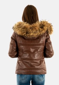 Chaqueta de cuero marrón con capucha forrada de piel, diseño acolchado y silueta ajustada. Acentuada con un suave borde de piel sintética.