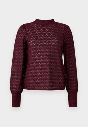 Burgundské dlouhé rukávy s vysokým výstřihem, zdobené texturovaným geometrickým vzorem a nařasenými rameny. Detail zapínání na knoflík na zadní straně.