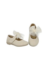 Zapatos Mary Jane beige con parte superior de malla texturizada y un lazo de encaje en el empeine. Suela de goma plana y diseño de punta redondeada.