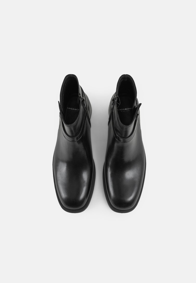 Czarne skórzane botki za kostkę z gładkim wykończeniem, okrągłym noskiem i zamkiem błyskawicznym z boku. Podeszwa ma lekkie wzniesienie. Prosty design.