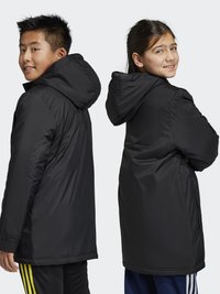 Chaqueta negra con capucha, diseño acolchado, de longitud media con puños elásticos. Dos modelos, uno de frente y otro de perfil, ambos mostrando el ajuste.