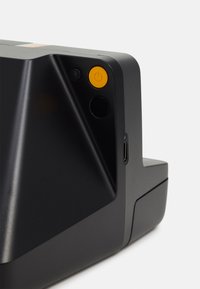 Compact black camera with angular design, yellow power button, and adjacent ports. Smooth texture with a matte finish.