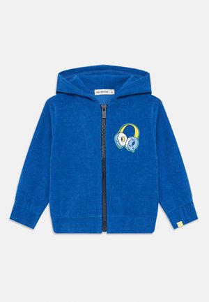 Blue corduroy zip-up hoodie featuring a hood, ribbed cuffs, and a graphic of headphones on the left chest. Soft texture with a relaxed fit.