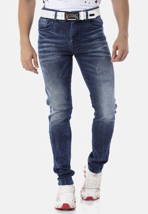Jean skinny en denim bleu foncé avec un motif délavé. Doté d'une ceinture blanche et de légères déchirures au niveau des cuisses.