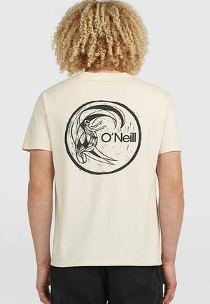 Person with curly blonde hair wears cream T-shirt with black circular surfer and wave graphic and O'Neill logo on the back.