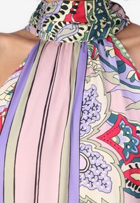 Top con scollatura a halter multicolore con motivi floreali e geometrici. Il tessuto è leggero e con una texture leggermente trasparente.