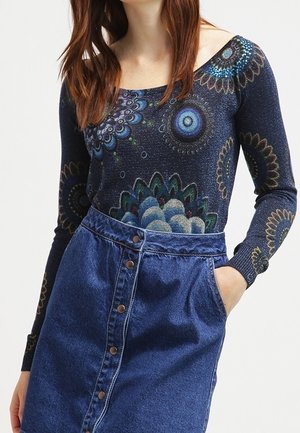 Haut à manches longues navy avec des motifs floraux, associé à une jupe en denim taille haute avec des boutons et des poches latérales.