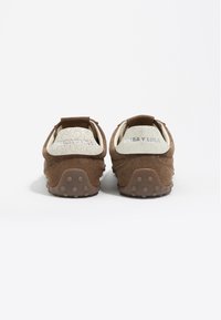 Brązowe zamszowe trampki z popękaną białą piętą i gumową podeszwą z wypukłymi kropkami. Logo "BIMBA Y LOLA" na pięcie.