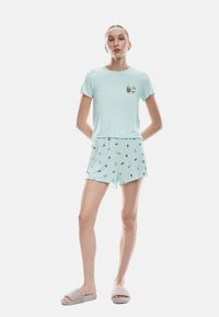 Helles mintgrünes Schlafanzugset mit einem kurzärmeligen Oberteil und gemusterten Shorts mit Eiswaffeldesigns. Weicher Stoff und lockere Passform.