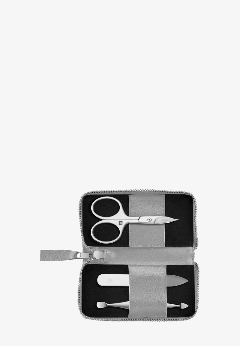 Set di strumenti per la cura personale in tonalità argento all'interno di una custodia grigia con zip. Include forbici, un limetta per unghie e due strumenti di forme e funzioni diverse su uno sfondo nero.