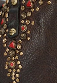 Borsa a tracolla in pelle marrone con borchie decorative oro e rosse, superficie testurizzata e una tracolla ornata con vari dettagli decorativi.