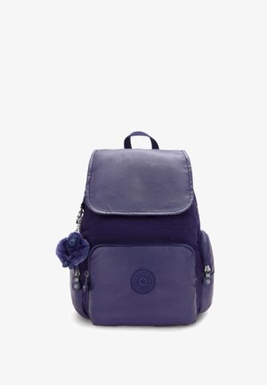 Sac à dos en nylon violet avec une poche avant, des poches latérales, un rabat en haut et un petit porte-clés en peluche attaché à la tirette de la fermeture.