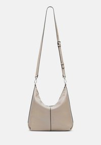 Beżowa skórzana torebka o zakrzywionym kształcie, z regulowanym paskiem i czarnymi akcentami w przeszyciach. Charakteryzuje się minimalistycznym stylem z zamknięciem na zamek błyskawiczny.