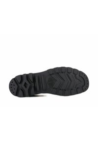 Suela de zapato de goma negra con un agarre texturizado y con patrón. Presenta surcos profundos e indentaciones circulares para mayor tracción. Diseño atlético estándar.