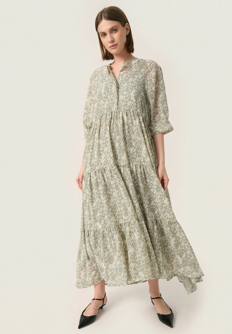 Vestido maxi de tejido verde claro con un patrón floral, que presenta un escote abotonado, mangas tres cuartos y un diseño en capas.
