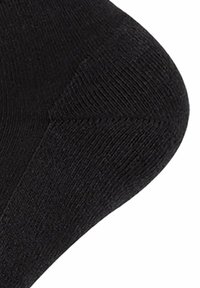 Calcetín negro con una textura suave, puntera reforzada y un diseño sin costuras. Presenta un patrón acanalado a lo largo del cuerpo y una forma cónica en el extremo.