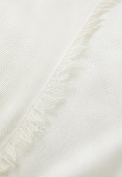 Biely tkaný materiál s jemným geometrickým vzorom a delikátnymi strapcami, s hladkou a mäkkou textúrou.