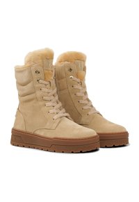 Béžové semišové kotníkové boty s umělým kožíškem, designem na šněrování, polstrovaným límcem a gumovými podrážkami s texturovaným hnědým vzorem pro lepší přilnavost.