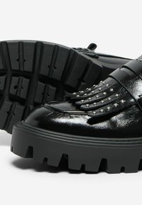 Scarpe in pelle verniciata nera con accenti a borchie e una spessa suola in gomma nera con battistrada profondo e una punta arrotondata.