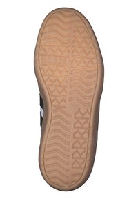 Podeszwa tenisówki Adidas z teksturowaną powierzchnią z gumy w kolorze naturalnym i wzorem w zygzak, widoczna czarno-biała górna część po bokach.