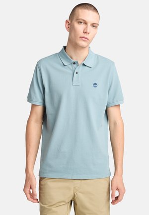 Polo azul claro hecho de algodón, con un cuello clásico, tapeta de dos botones y un pequeño logo en el lado izquierdo del pecho. Mangas cortas.