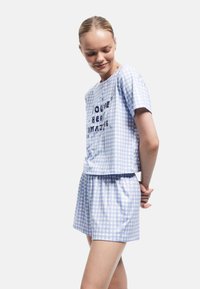 Blau-weißes Karo-Schlafanzug-Set mit kurzen Ärmeln und Shorts. Auf der Vorderseite befindet sich der Drucktext "DU BIST BERRI AMAZING!" Weicher Stoff.