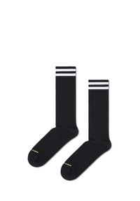 Μαύρες αθλητικές κάλτσες με λευκές ρίγες στον ποδόγυρο και κίτρινο λογότυπο στο δάχτυλο. Φτιαγμένες από μαλακό και ελαστικό ύφασμα.