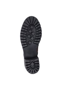 Zwarte rubberen zool van een laars met een robuust loopvlakpatroon dat verhoogde kruissymbolen en diepe groeven bevat voor grip en duurzaamheid.