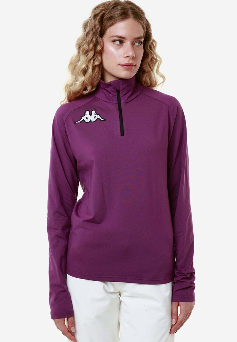 Maglia atletica a maniche lunghe, con zip e collo alto, di colore viola, con una finitura testurizzata; presenta un logo bianco sul petto sinistro e maniche aderenti.