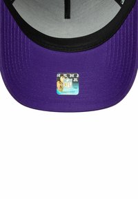 Lila Kappe mit schwarzem Schirm, versehen mit NFL-Branding und einem holographischen Aufkleber im Inneren. Die Stoffe Textur ist glatt und gewebt.