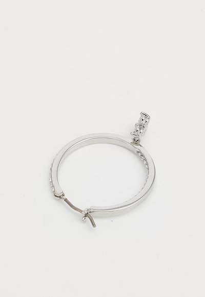 Srebrna obročasta uhanska s majhnimi vgrajenimi kristali in okrasnim zaklepom na enobarvni beli podlagi.