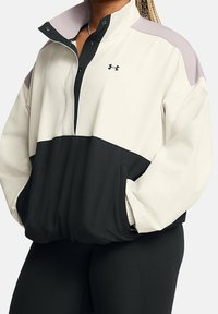 Pullover jacket featuring a cream, black, and lavender color block design, made of soft material with a zippered collar and front pockets.
