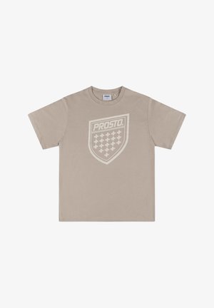 Beżowy bawełniany T-shirt z krótkim rękawem, z dużą, jasną grafiką tarczy z napisem "PROSTO" oraz wzorem siatki w środku.