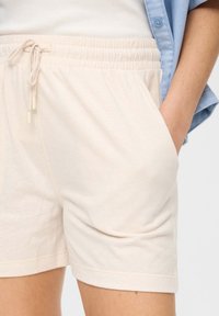 Lichtbeige katoenen shorts met een elastische tailleband, trekkoordsluiting en zijzakken. Soepele textuur met een ontspannen pasvorm.